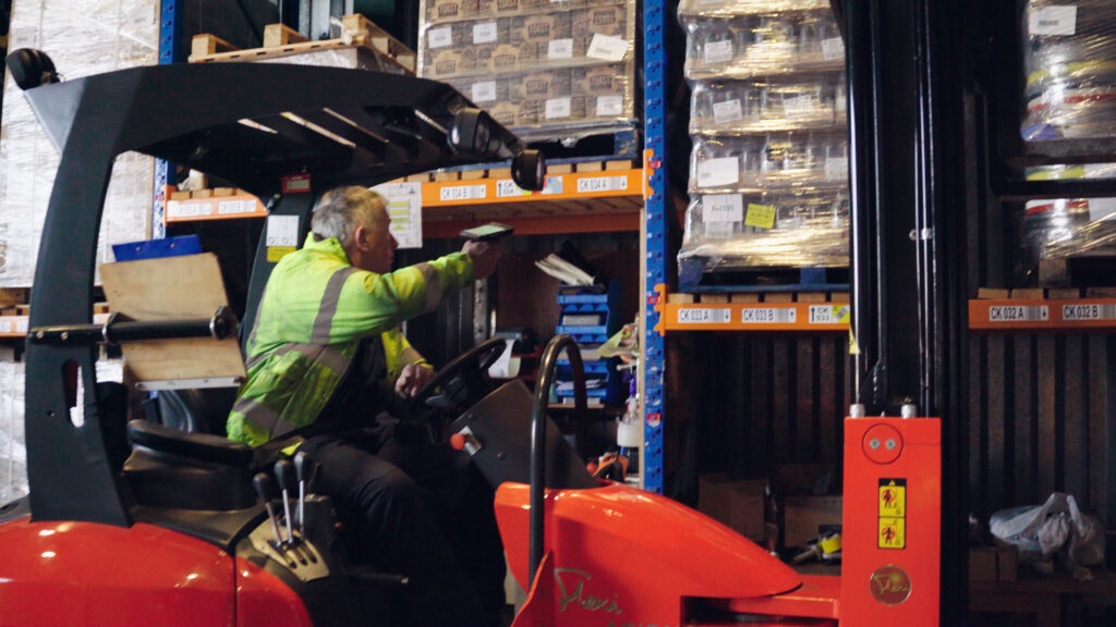 Scanning on a forklift | clarus wms Operative on a forklift using a handheld scanner beside pallet racking at st john's hall storage