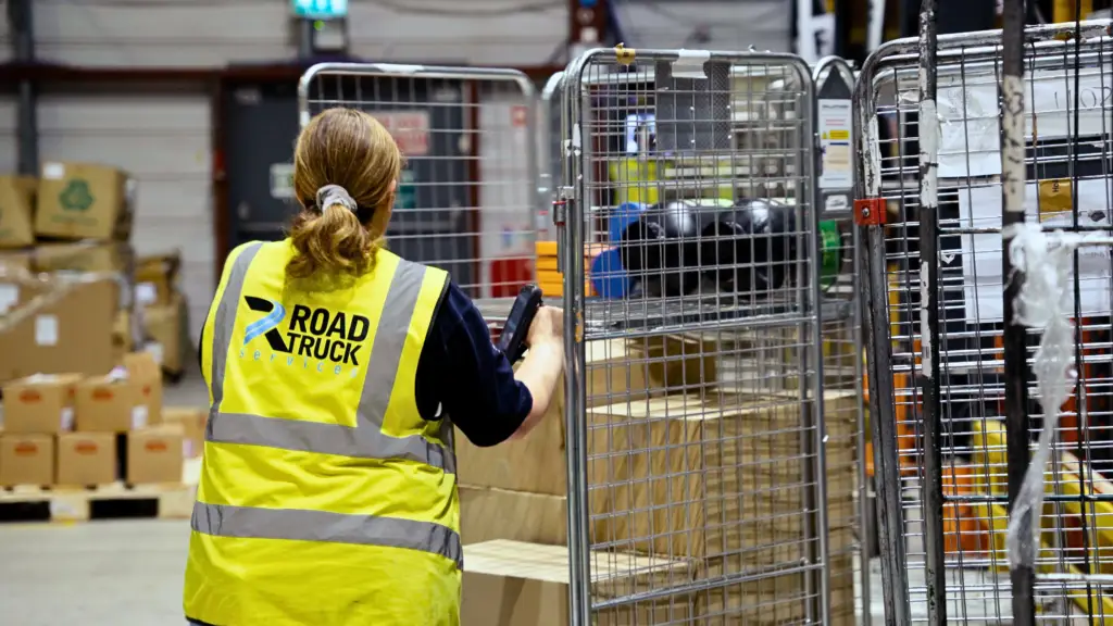 Road truck services female employee pushing crate in warehouse